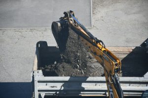 Экскаватор загружает грунт в самосвал